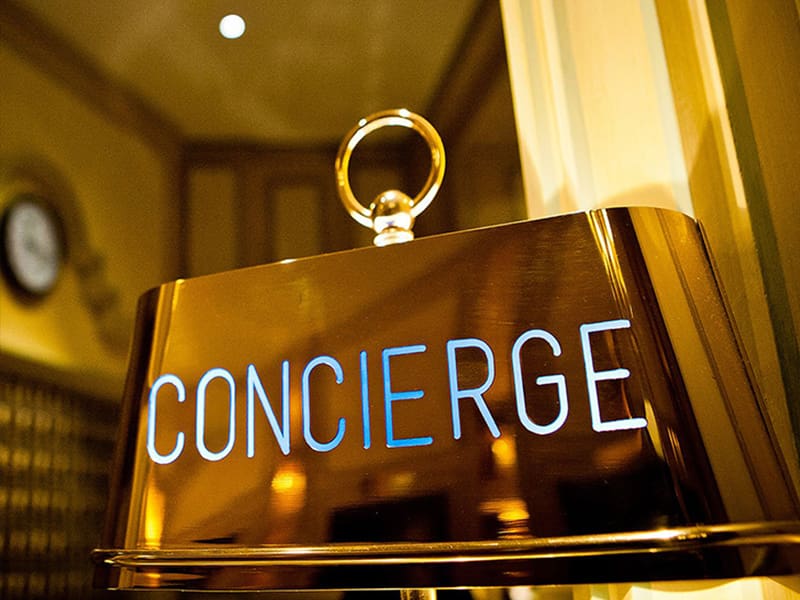 A concierge sign hanging from the ceiling of a hotel room.