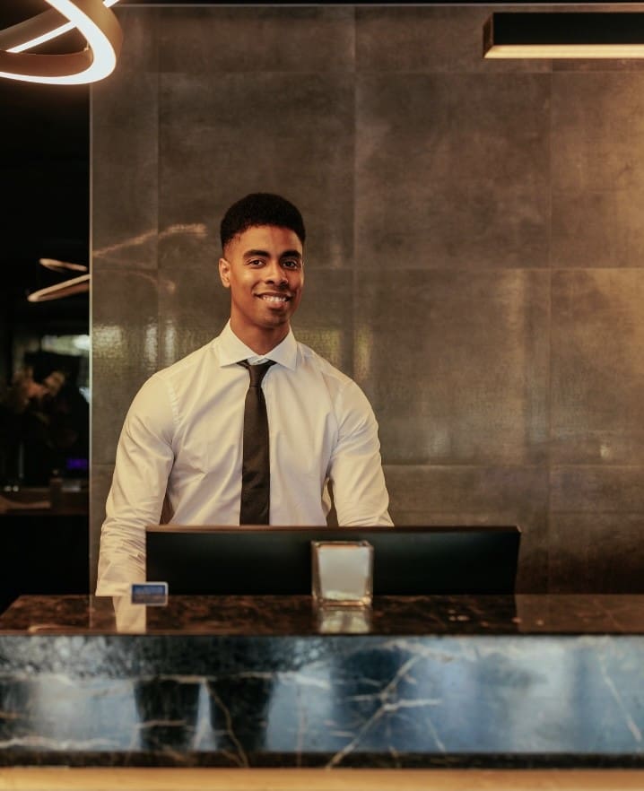 A man standing behind the counter of a hotel room.