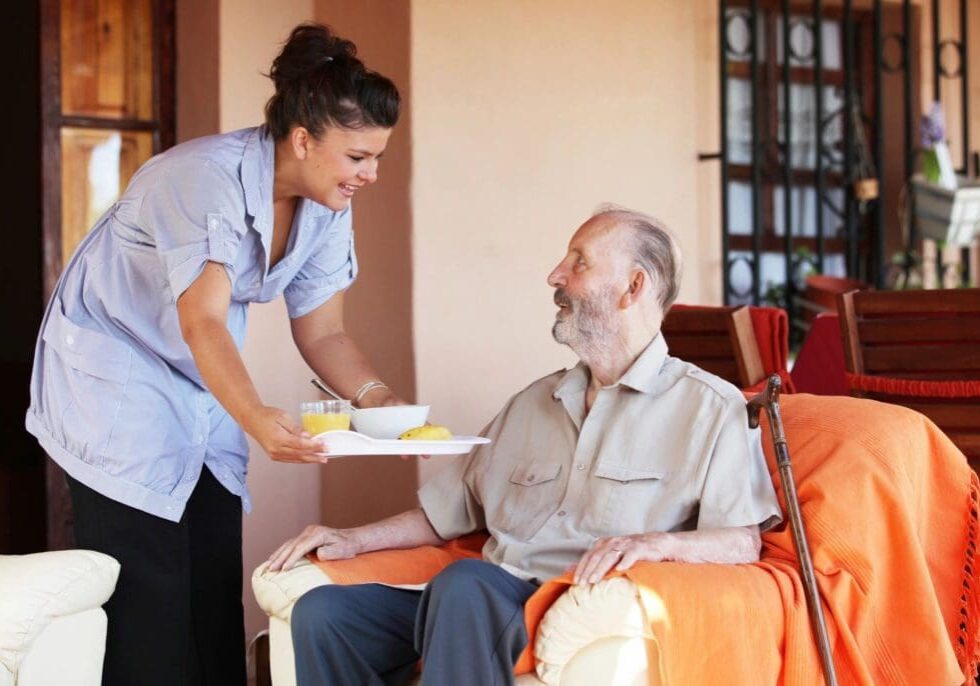 A woman serving food to an older man.